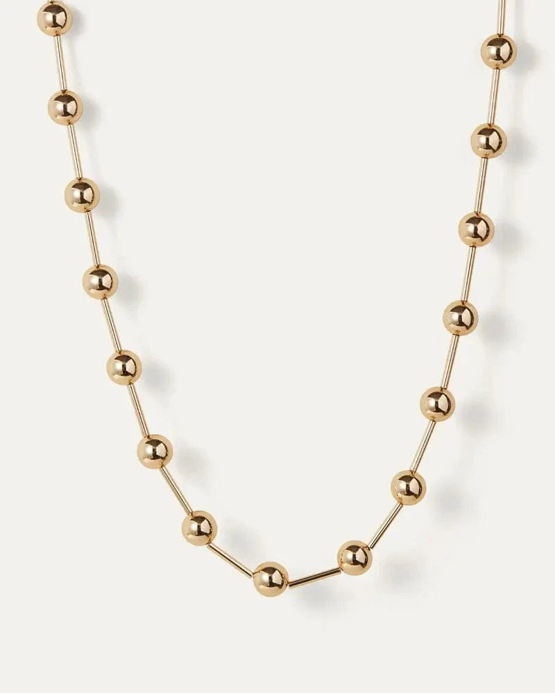 Gold Celeste Necklace by Jenny Bird, laid flat on white background, showcasing high-polish finish and luminous spheres.