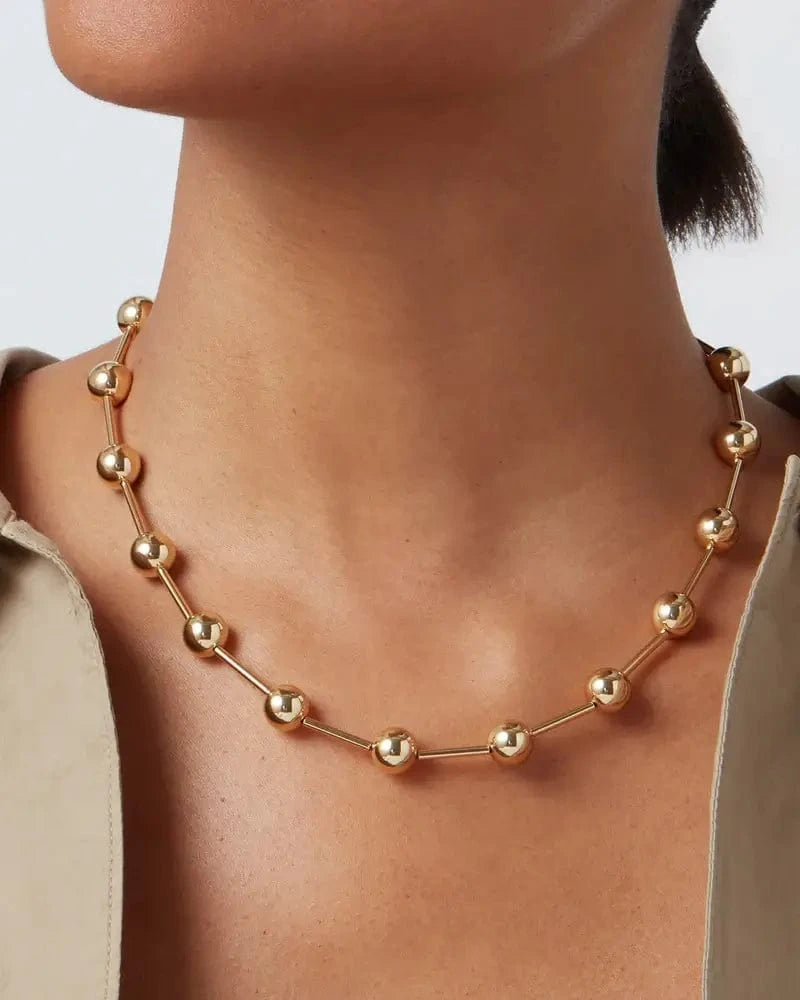 Close-up shot of gold Celeste Necklace by Jenny Bird worn on model, showing elegant design and luminous spheres.