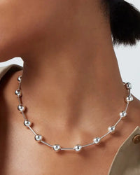 Close-up shot of silver Celeste Necklace by Jenny Bird worn on model, featuring elongated metal beads and modern elegance.
