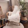 A white throw placed on a wooden chair in the corner of a living room.