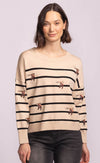 Front view of Cruz Sweater featuring embroidered swallows on beige and black stripes, styled with dark denim.