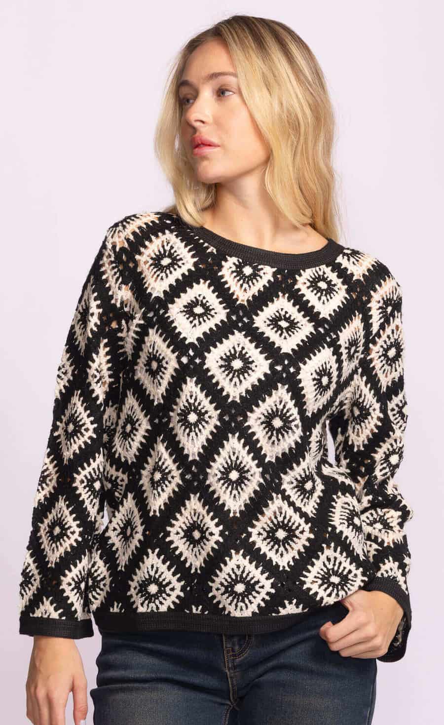 Woman wearing Dina Sweater by Pink Martini, black and cream crochet knit, styled with jeans