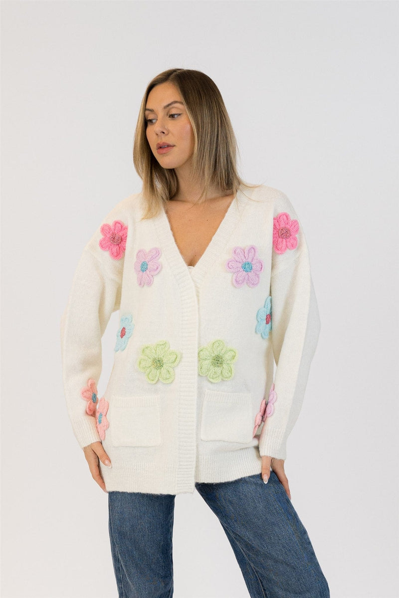 Front view of the Elska cardigan by Lyla & Luxe showing pink, blue, green, and lilac 3D knit flowers on a white knit background.