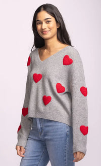 Side view of grey Espera Sweater with bold red hearts and drop shoulders