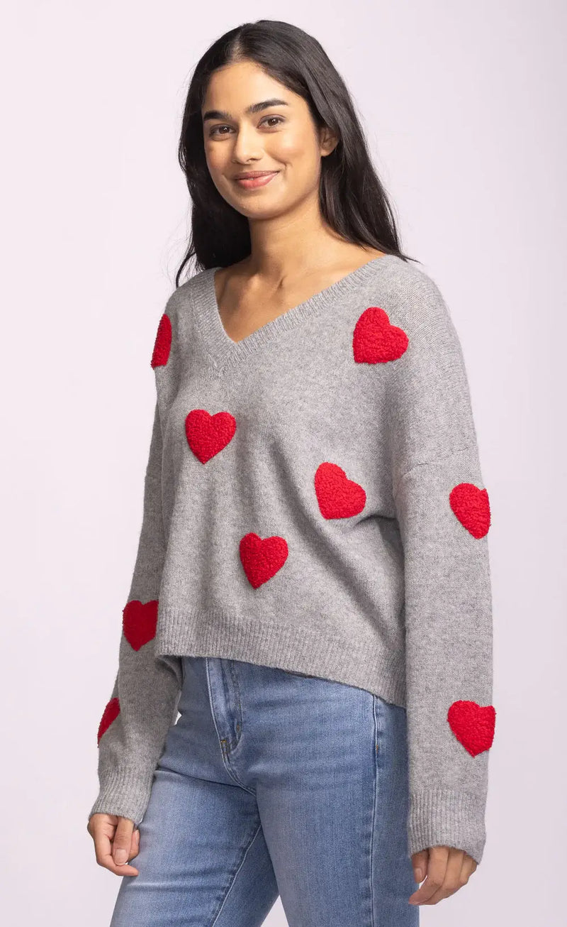 Side view of grey Espera Sweater with bold red hearts and drop shoulders