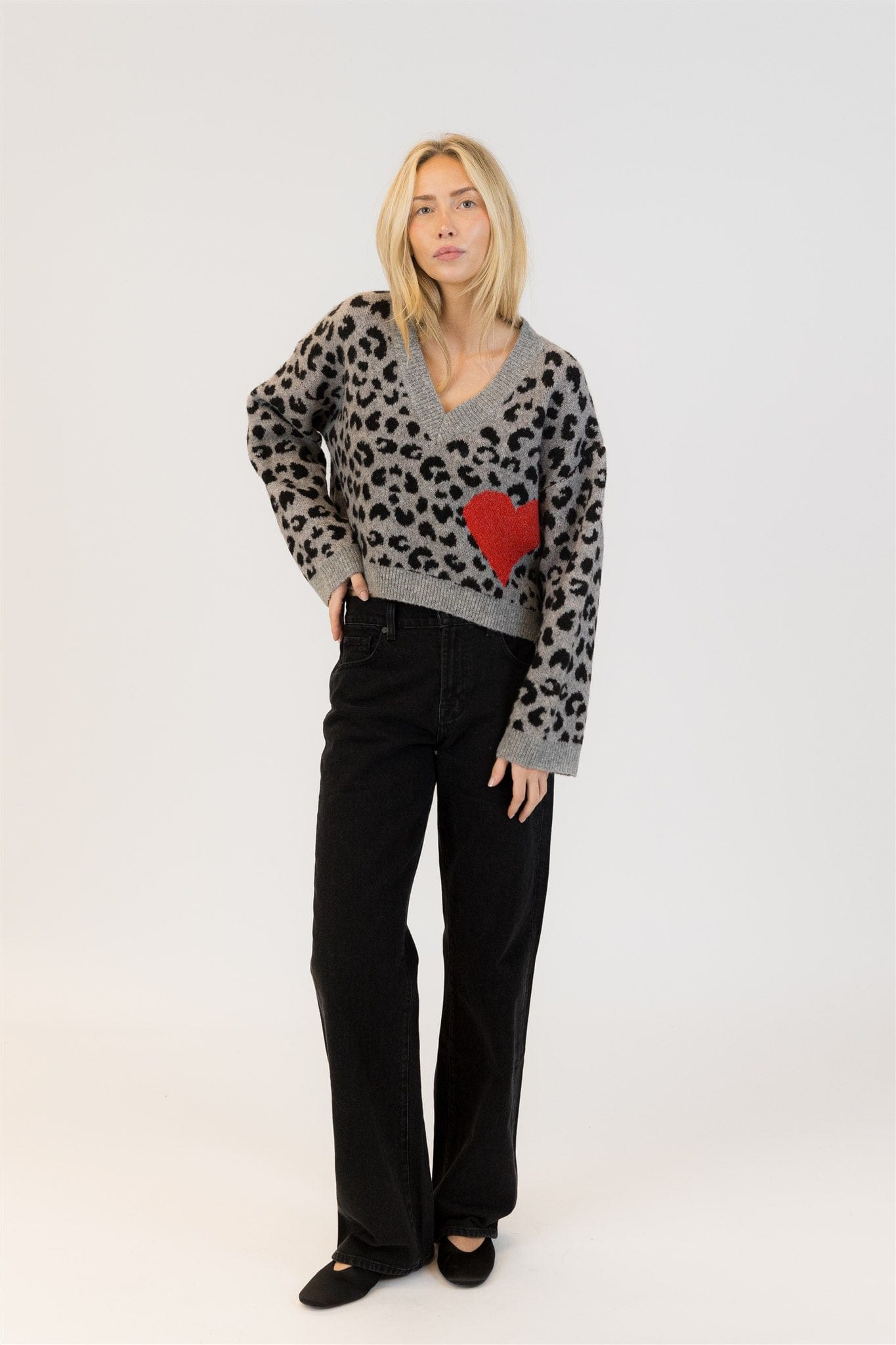 Woman wearing Lyla & Luxe Elska cardigan in pale blue with navy heart print, standing against a white background – available at Lemonberry in Aurora, ON

