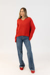 Woman wearing a red sweater and blue jeans on a white background