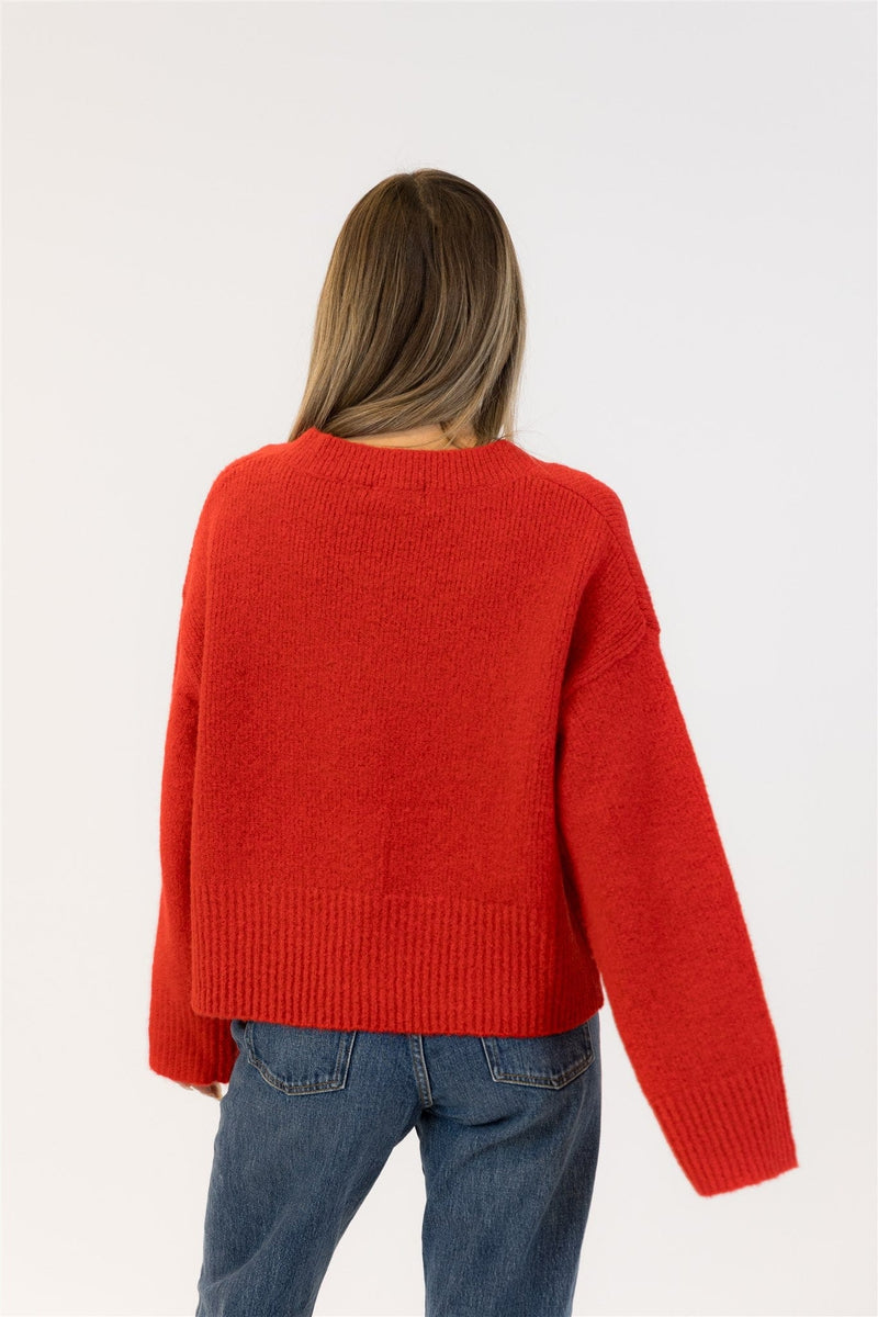 Person wearing a red sweater and blue jeans on a white background
