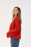 Woman wearing a red sweater and blue jeans on a white background