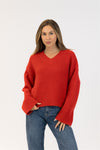 Woman wearing a red sweater and blue jeans on a white background