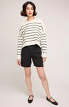 Full-body view of woman in striped Gentle Fawn Echo sweater and black shorts, posed casually on white background