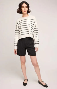 Full-body view of woman in striped Gentle Fawn Echo sweater and black shorts, posed casually on white background