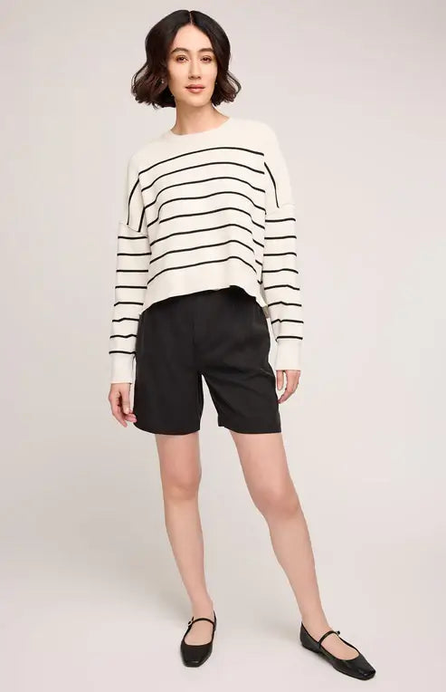 Full-body view of woman in striped Gentle Fawn Echo sweater and black shorts, posed casually on white background