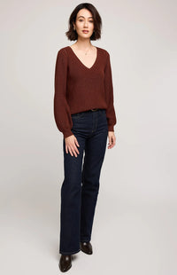 Woman wearing Gentle Fawn Hailey Sweater in mahogany, v-neck with balloon sleeves and dark jeans on a white background.