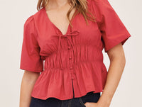 Close-up of the Gentle Fawn Iona Tie Front Blouse in Cranberry showing tie neckline and smocked waist
