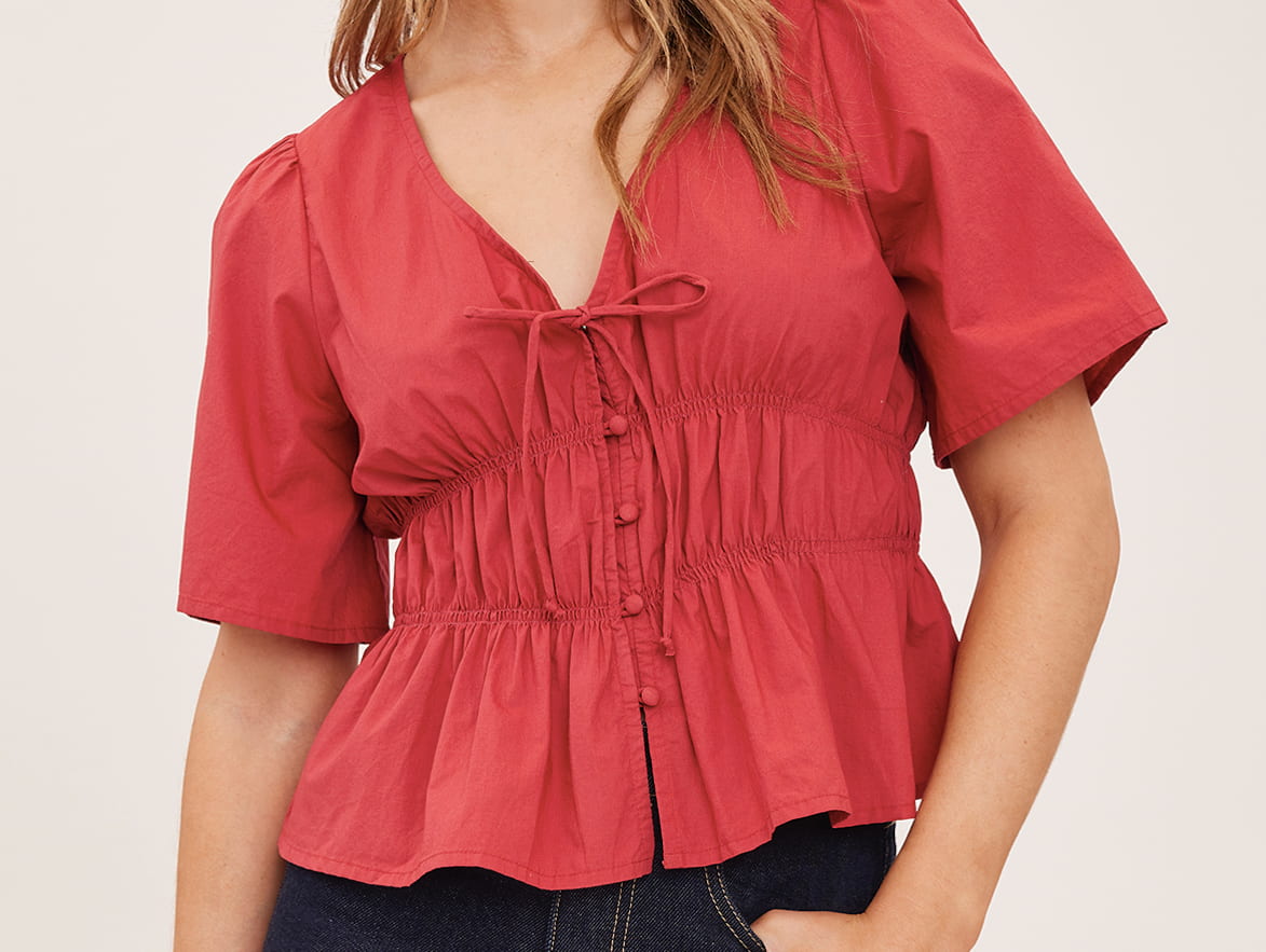 Close-up of the Gentle Fawn Iona Tie Front Blouse in Cranberry showing tie neckline and smocked waist