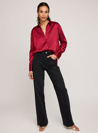 Woman wearing Gentle Fawn's crimson Simone blouse with black pants on a plain background