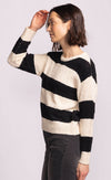 Side view of model wearing Pink Martini Glynn Sweater in black and cream stripes, styled with high-rise charcoal denim.