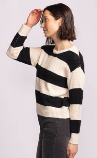 Side view of model wearing Pink Martini Glynn Sweater in black and cream stripes, styled with high-rise charcoal denim.