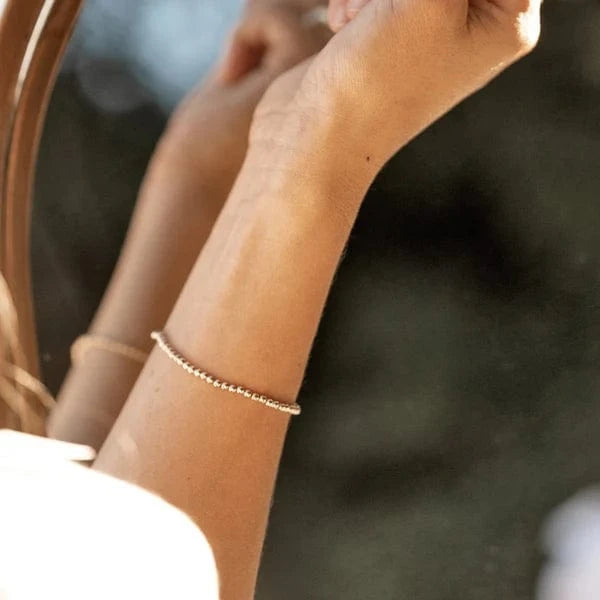 Shiny Soul Gold Intention Bracelet worn on wrist in natural light – delicate 14k gold beads glowing in the sun