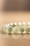 Close-up of Angelite bracelet beads in soft green under warm natural lighting

