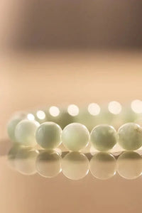 Close-up of Angelite bracelet beads in soft green under warm natural lighting


