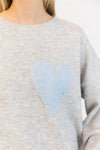 Close-up of stitched blue heart on grey knit sweater
