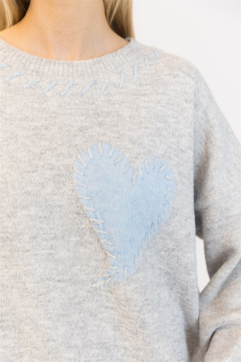 Close-up of stitched blue heart on grey knit sweater