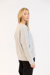 Model in grey pullover with subtle heart patch, casual styling