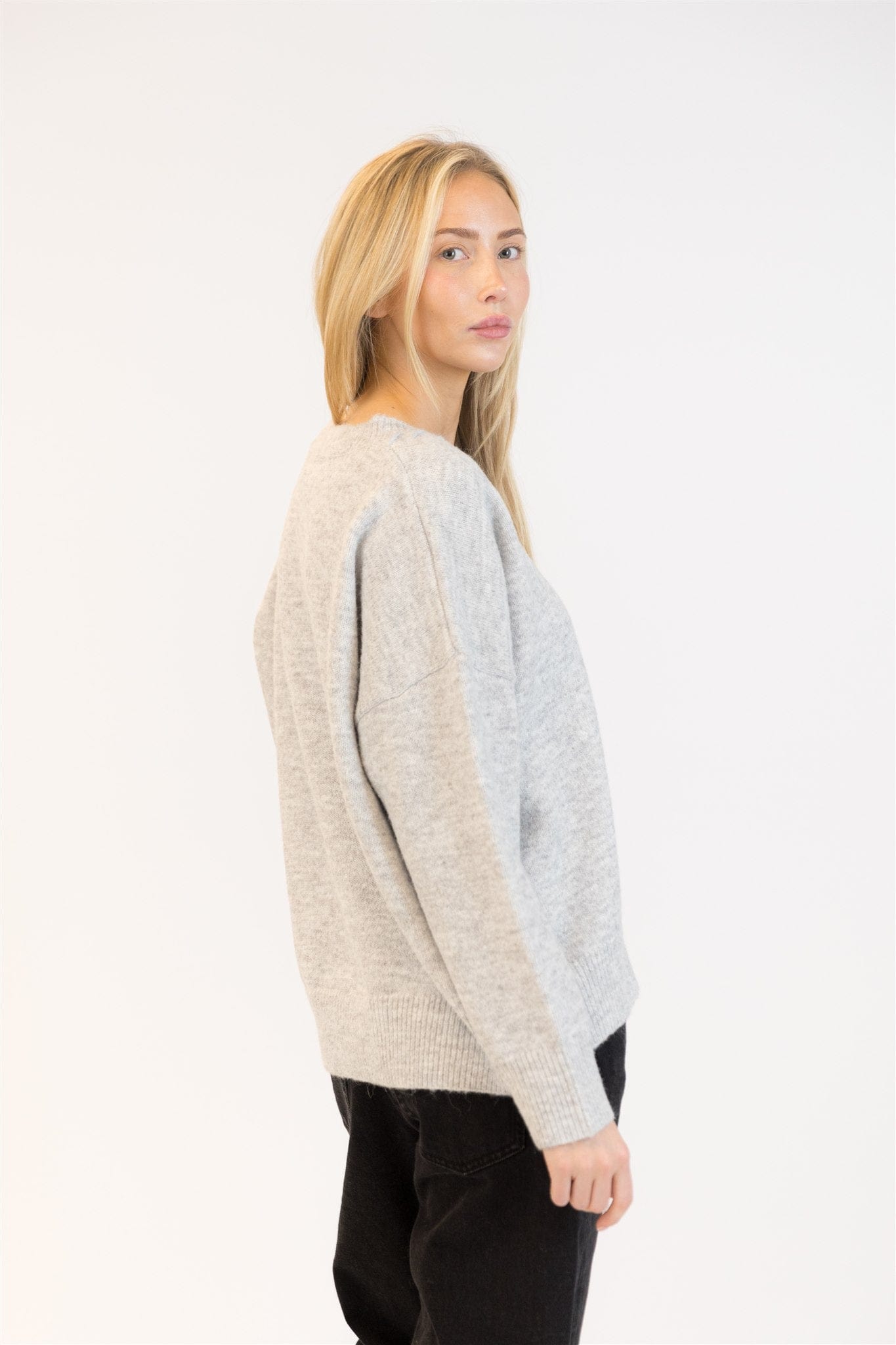 Model in grey pullover with subtle heart patch, casual styling