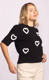 Side profile of black sweater with puff sleeves and white heart accents.