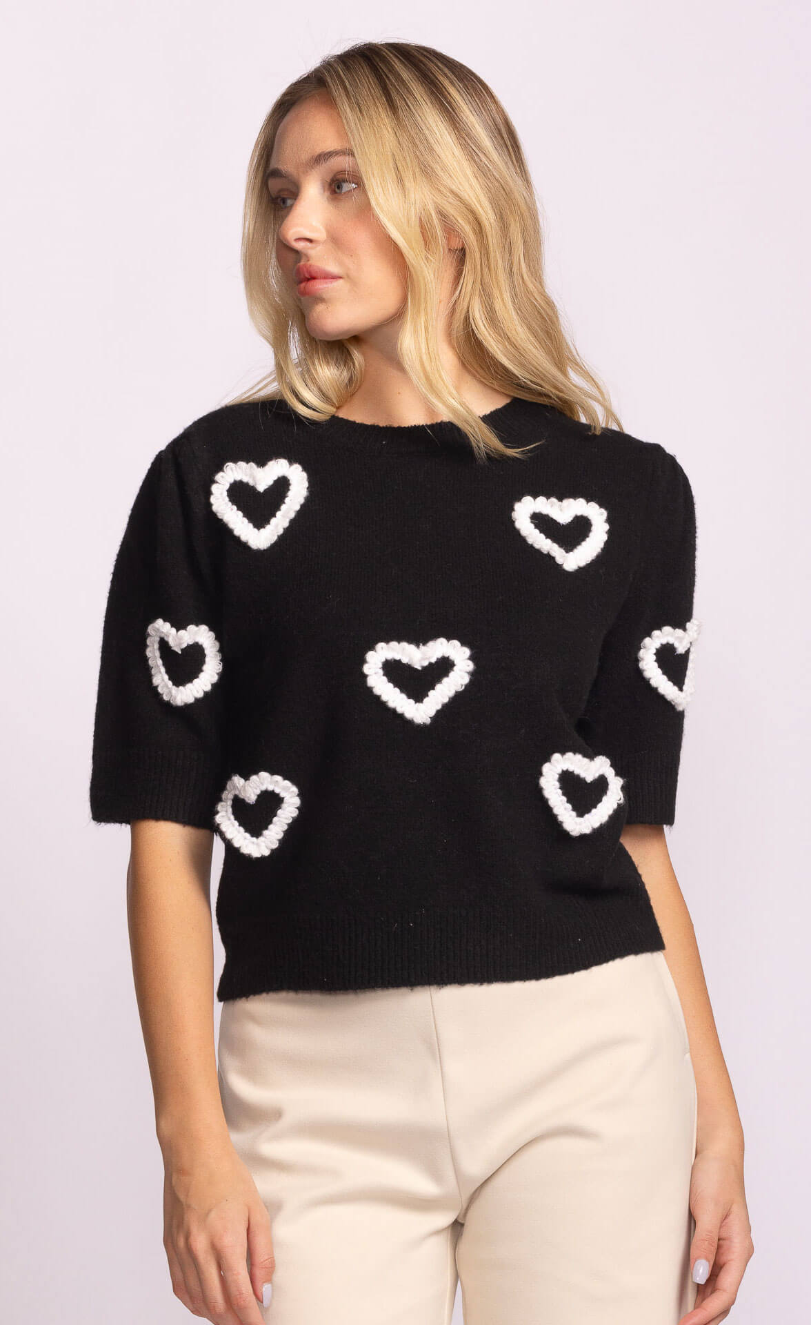 Front view of black sweater with white heart motifs, playful knit by Pink Martini