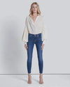 Close-up front view of high-waisted skinny jeans, showing button closure, zip fly, and stretch denim texture.