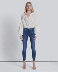 Close-up front view of high-waisted skinny jeans, showing button closure, zip fly, and stretch denim texture.