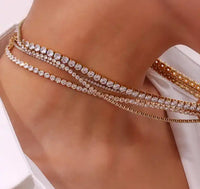 Hoopla gold tennis necklace layered with other chains on model Lemonberry Aurora