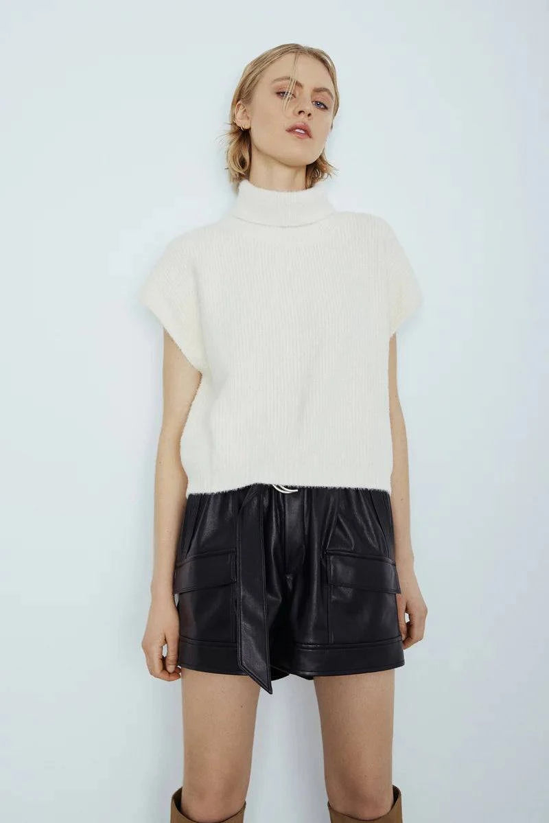 Model in white Jack Sweater and high-waisted leather shorts, front view.