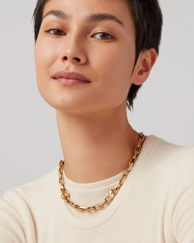Close-up of Jenny Bird Art Heart Chain Necklace worn at neckline with ivory top