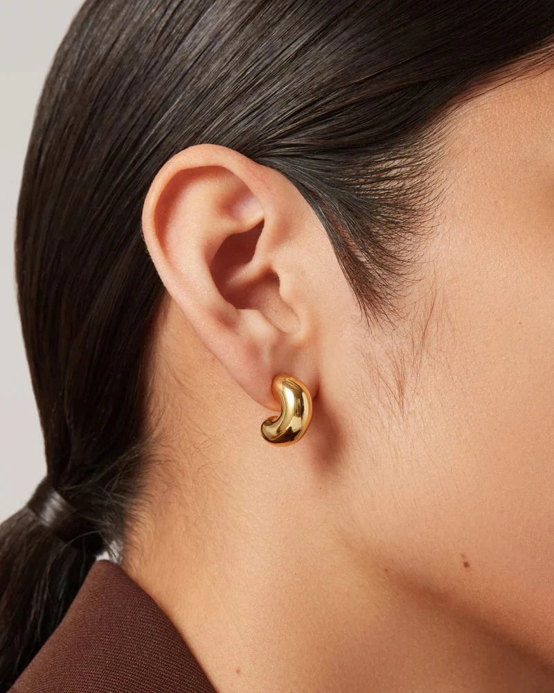 Gold earring worn by a person with a neutral background