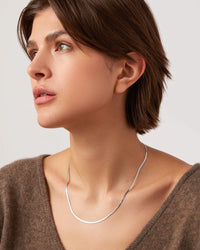 Jenny Bird Zeina Slim Chain silver herringbone necklace worn flat against the neckline