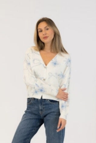 Lyla & Luxe Kailiebow cardigan in white with blue bow and floral print, worn with jeans, available at Lemonberry