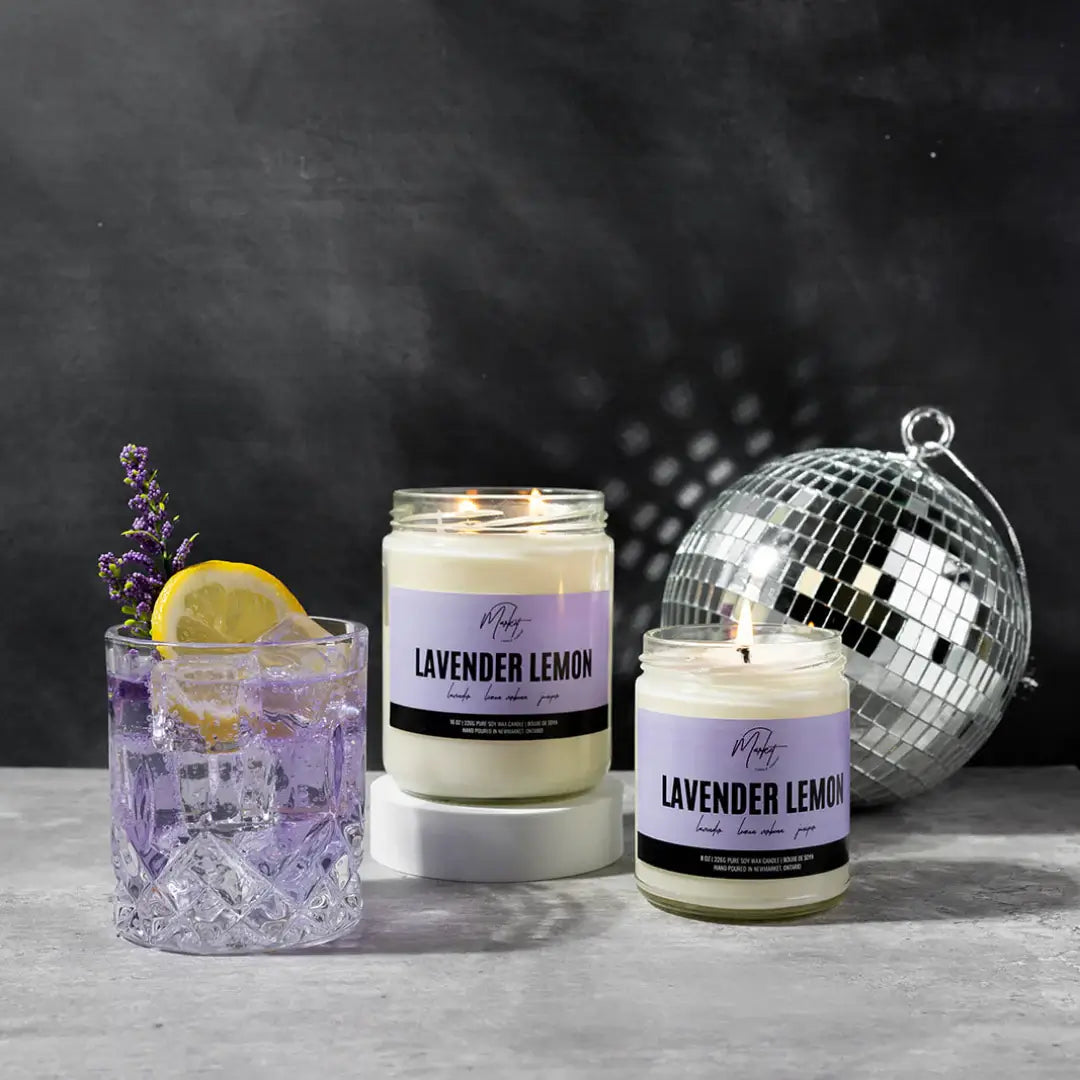 Lavender lemon candle by Market Candle Company, displayed beside a cocktail and a glitter ball. 