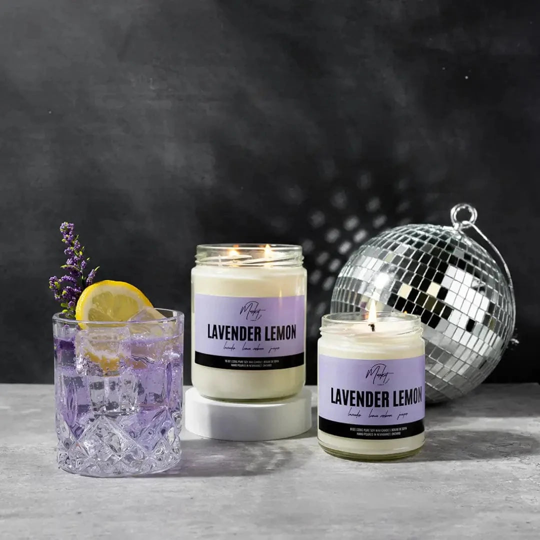 Lavender lemon candle by Market Candle Company, displayed beside a cocktail and a glitter ball. 