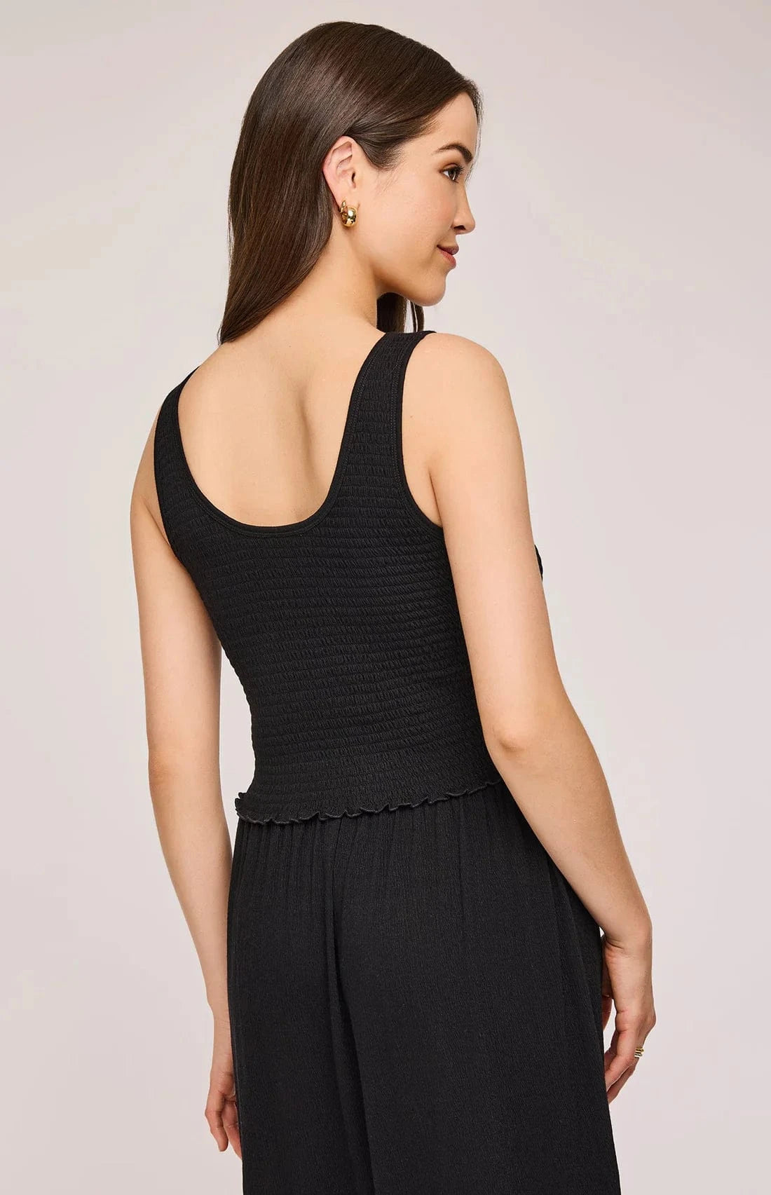 Back view of the Gentle Fawn Layla Tank in black. Shows full smocked texture and cropped cut with a subtle ruffle hemline.