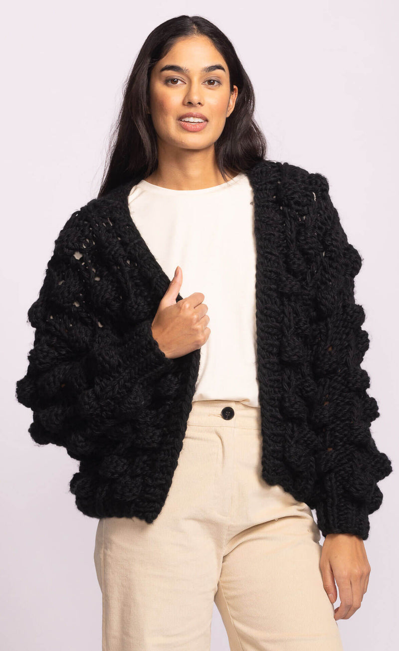 Close-up of Pink Martini Raya Sweater in black, highlighting dramatic bubble knit sleeves and textured open-front design – Lemonberry boutique.