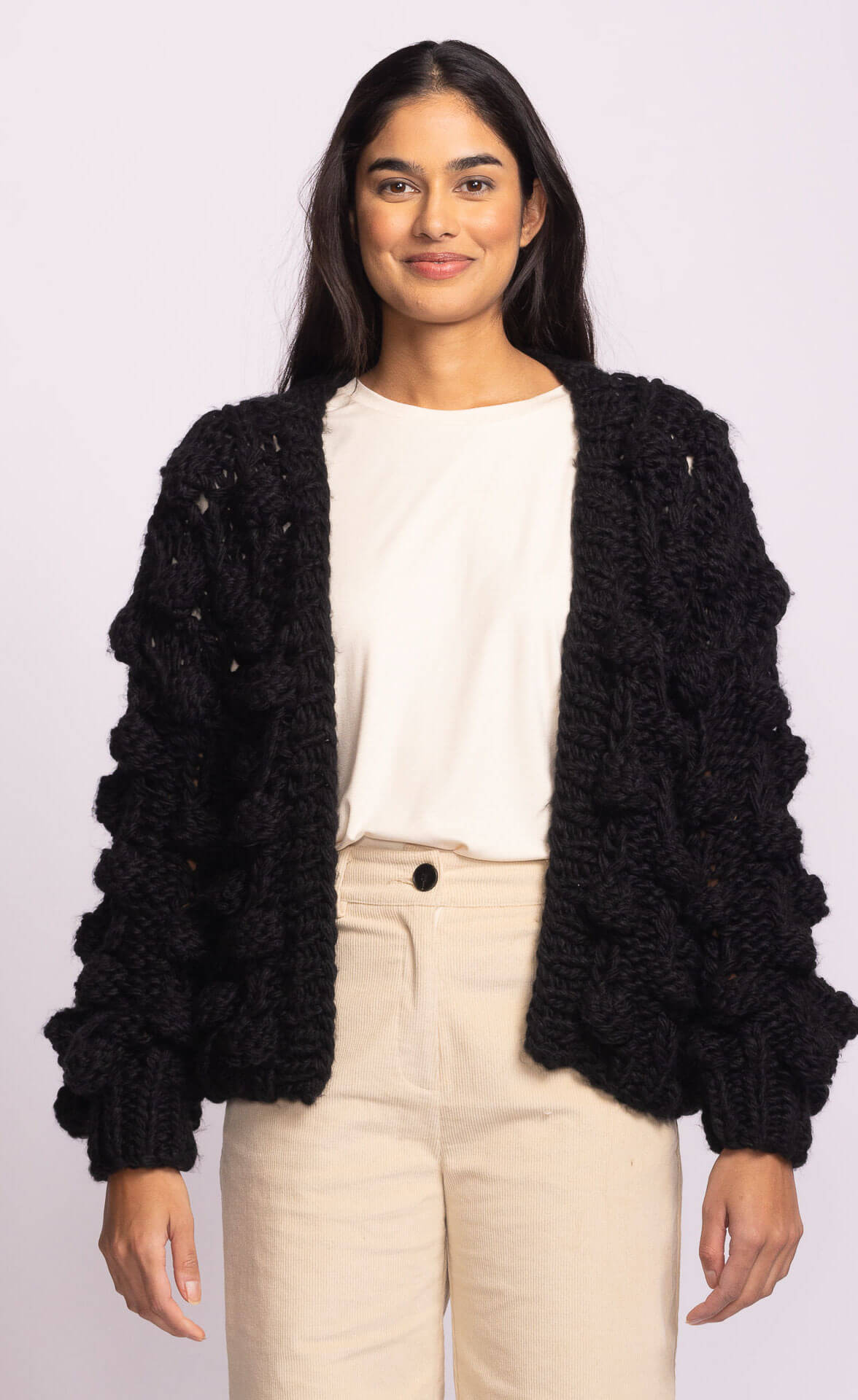 Side view of Raya Sweater by Pink Martini in black, showcasing bubble sleeve detail and relaxed chunky knit – shop Lemonberry Aurora or online.