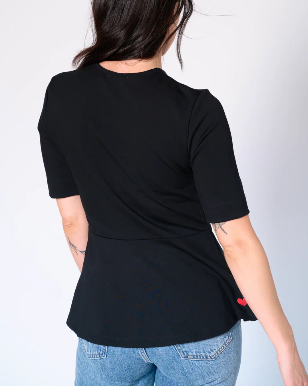 Back view of black Preloved Lisa Peplum Top with signature upcycled red heart patch