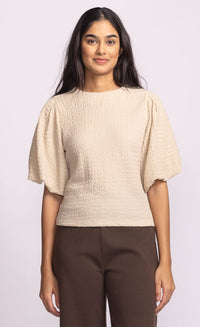 Model wearing Pink Martini Lita Top in beige with puff sleeves, front view.