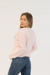 Woman wearing a light pink sweater and blue jeans on a white background