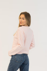 Woman wearing a light pink sweater and blue jeans on a white background