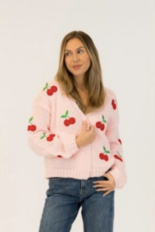 Model wears Lyla + Luxe Lexi pink cardigan with red cherry embroidery, styled casually with jeans